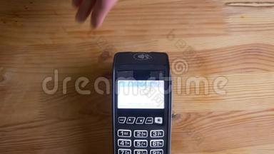 一个支付终端的特写镜头，用于支付手机上的应用程序在室内。 手被扫描